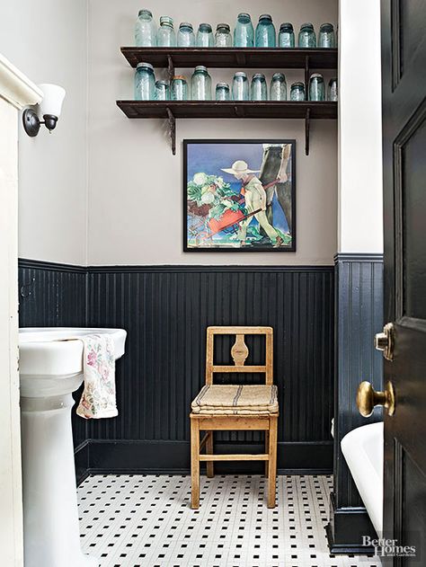 The molding top and bottom beadboard.......,,,,,,,,,,little bit country, a little bit cottage, this bathroom pays tribute to long-ago lavatories in modern ways. References to farm life include a rural rendering, a canning-jar collection, and a primitive coverlet folded on an antique chair. The tiled floors and black painted wainscoting give a nod to cottage style in high-impact fashion. Country Cottage Bathroom, Country Bathroom Designs, Black Wainscoting, Wainscoting Stairs, Painted Wainscoting, Cottage Bathroom Ideas, Cottage Bath, Wainscoting Bathroom, Primitive Bathrooms