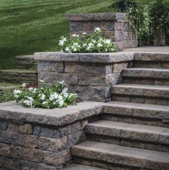 Stair or step planters can take a variety of shapes and styles. Options can include symmetrical tiers, terraced landings, or a singular accent planter. #planter Front Porch Stone Steps, Front Porch Stone, Backyard Retaining Walls, Patio Stairs, Front Porch Steps, Landscape Stairs, Front Door Steps, Patio Steps, Stone Steps