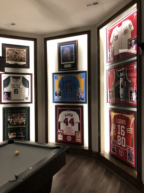 Framed Jerseys On Wall Bedroom, Sports Memorabilia Display Ideas Framed Jersey, Hockey Jersey Frame, Moody Sports Basement, Sporty Basement Ideas, Man Cave Jersey Display, Framed Sports Jersey, Basketball Jersey Display Ideas, Sports Bar Man Cave