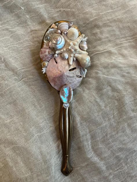 One of a kind upcycled vanity hair brush made with seashells, diamonds, pearls, coral, miscellaneous jewelry, starfish, abalone, sand dollar, and other oceanic materials ✨🫧  Approximately 3 inches wide by 1p inches long, handle with care it's delicate 🐚 Mermaid Hair Brush, Pearl Core Aesthetic, Mermaid Core Room Decor, Mermaid Trinkets, Upcycled Vanity, Brush Aesthetic, Mermaid Items, Sand Jar, Seashell Diy