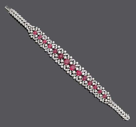 RUBY AND DIAMOND BRACELET, ca. 1950. White gold 750, 38g. Of floral design, set with 14 graduated, round rubies of ca. 6.00 ct, brilliant-cut diamonds weighing ca. 2.50 ct and decorated with diamond-set leaf motifs totalling ca. 1.80 ct. L White Gold Diamond Bracelet With Ruby, Luxury Ruby Diamond Bracelet For Formal Occasions, Luxury Red Diamond Jubilee Bracelet, Luxury Ruby Elegant Bracelet, Luxury Ruby Diamond Bracelet, Art Deco Diamond Jewelry, Ruby Ring Designs, Woman Ring, Elegant Jewellery