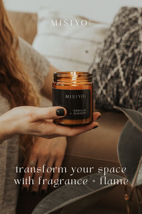 The photo says "transform your space with fragrance + flame" and an amber candle jar is shown being held in a woman's hand while burning. She is in a cozy living room and next to a plant and some plush black and white pillows. Candle Ads, Beeswax Scented Candles, Creative Advertising Photography, Candles Photography, Coconut Wax Candles, Single Candle, Clean Fragrance, Selling Candles, Outdoor Advertising