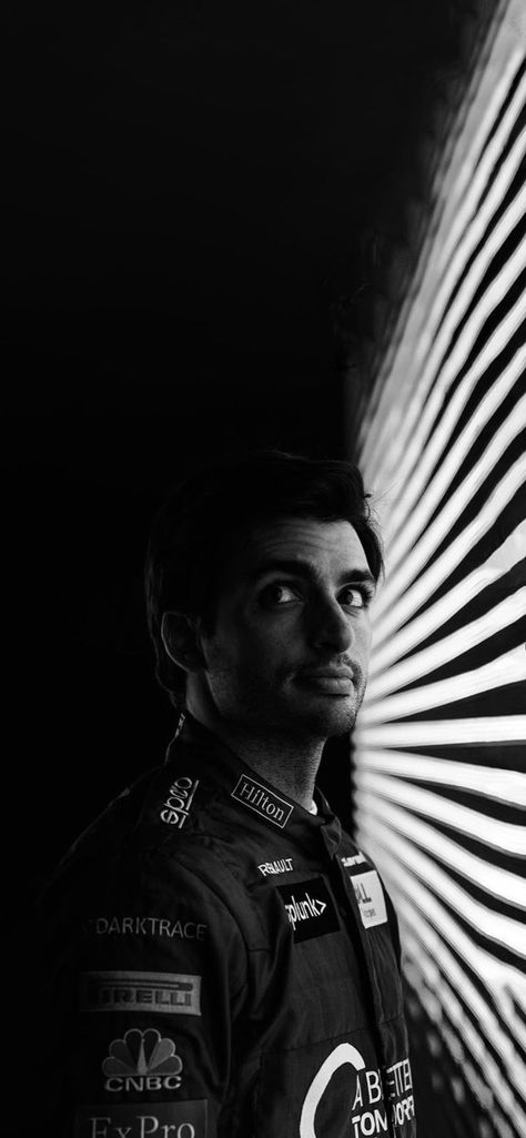 This is a wallpaper the size of an iPhone 12 screen. It's a black and white photograph with a predominancy of dark shades. Gorgeous driver Carlos Sainz Junior (we can also call him Chili) is the star here. He is standing near a light source (is seems to be blinds) and he's looking up to his right side. You see very little of his uniform, you see the logos of his sponsors but you don't see the Ferrari logo but his beauty is very appreciated. Carlos Sainz Jr Wallpaper, Sainz Wallpaper, F1 Driver, Car Hd, Wallpaper For Iphone, Smooth Operator, Ferrari F1, F1 Drivers, Car And Driver