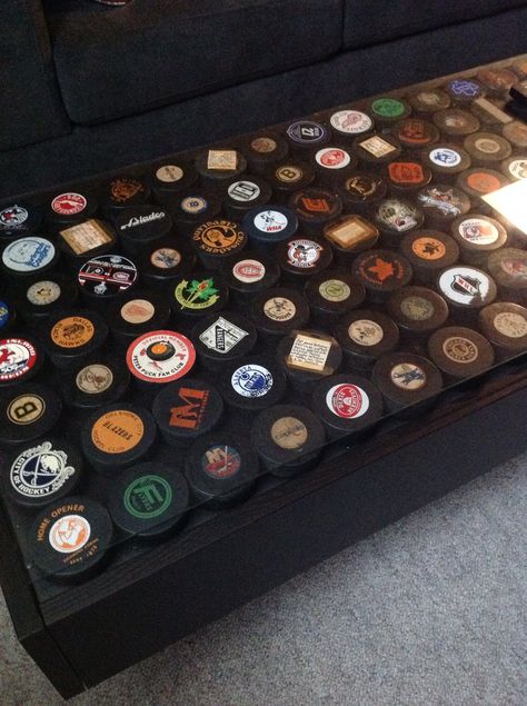 She wasn't big on the idea at first, but our basement is now complete with our hockey puck coffee table.. We love it! Part ikea hack, part storage, 100% family heritage. Mancave Coffee Table Ideas, Hockey Bar Ideas, Ice Hockey Room, Bat Storage, Part Storage, Lakeview House, Hime Decor, Sports Den, Hockey Room