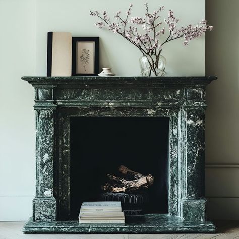 A rich, dark green marble fireplace is the centerpiece of this room, showcasing the beauty of marble as a building material. The intricate white veining offers a striking contrast to the light walls, making this fireplace a timeless and elegant choice for those seeking to incorporate durable materials in home design. Paired with simple decor, this setup adds warmth and sophistication to any living space. Marble Fireplace Living Room, Green Marble Fireplace, Marble Building, Building Materials Architecture, Dark Green Marble, Light Walls, Timeless Living Room, Fireplace Living Room, Marble Fireplace