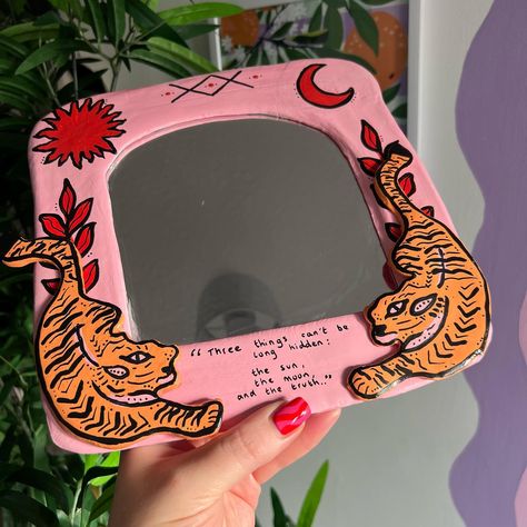 The tiger mirror🐅 💖🧡 “three things can’t be long hidden; the sun, the moon and the truth..” #colourfulhomedecor #smallbusiness #mirror #airdryclay #etsyshop Clay On Mirror, Mirror Clay Art Ideas Aesthetic, Ceramic Art Mirror, Funky Clay Mirror, Clay Decorated Mirror, Clay Mirror, Small B, Ceramics Ideas Pottery, Mirror Designs