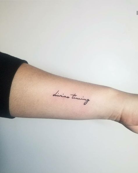 Small divine timing tattoo in script  #divinetiming #divinetimingtattoo #divinetimingscript #smalltattoo #smallscript #divinescript #timingscript #divinetimingart Remain Tattoo, Divine Timing Tattoo Ideas, Divinity Tattoo Word, Divine Time Tattoo, In Divine Timing Tattoo, Divinely Guided Tattoo, Divine Script Tattoo, Divinely Protected Tattoo, Timing Tattoo