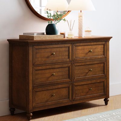 Elegant pieces don't have to be flamboyant or over the top. This contemporary dresser proves that even the simplest designs can be sophisticated and charming. It's right for almost any occasion and makes any space look amazing especially the bedroom. This is a wood 6-drawer dresser with storage for clothing, bedding, accessories, and more. Large ring decorative hardware pulls on the four standard drawers and small knobs for the three centre drawers all in a champagne brass finish. The sleek dark Solid Wood Dressers, Rustic Wood Dresser, Accent Dresser In Bedroom, Dresser In Front Of Bed, Small Room Dresser Ideas, Dresser Dark Wood, Dresser With Storage, Dark Wood Dresser, Rotational Grazing