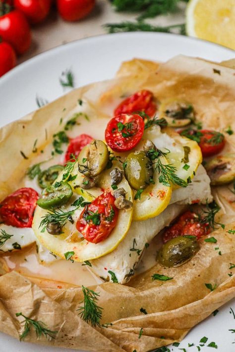 Baked Cod in Parchment Paper is all about the 3 f’s: fresh, flavorful, flaky! Cooked low and slow, it yields tender fish topped with sliced lemon, tomatoes, capers, olives, and fresh herbs. The best part is that it takes just 30 minutes to make! This baked Mediterranean cod recipe is a delightful addition to your weeknight dinner rotation. It's topped with fresh ingredients then steamed in parchment paper, a method known as en papillote in French and al cartoccio in Italian. Fish Papillote, Roasted Chicken Thighs And Vegetables, Cod In Parchment, Mediterranean Cod, Miso Salmon Recipe, Pistachio Crusted Salmon, Sliced Lemon, Miso Glazed Salmon, Cod Recipe