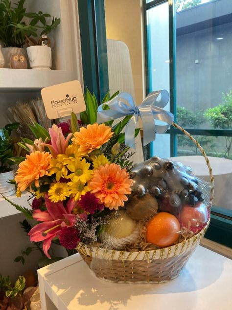 Gerbera and lilies in fruit basket arrangement. Bright and colourful flowers as gift. Fruit Basket Arrangement, Basket Arrangement, Colourful Flowers, City Centre, Fruit Basket, Colorful Flowers, Lily, Fruit, Photo And Video