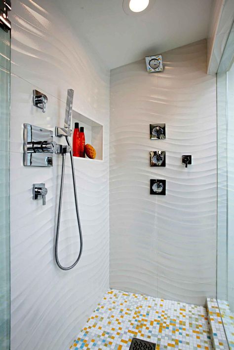 A waved effect on these shower walls create a water like movement in the space. Small tile flooring keeps with the bright look and adds freckles of yellow, gray and blue. Textured Tiles Bathroom, White Tile Bathroom Walls, Shower Tile Ideas, Modern Bathroom Tile, Bathroom Shower Walls, Tile Layout, White Bathroom Tiles, Contemporary Shower, Bathroom Shower Tile