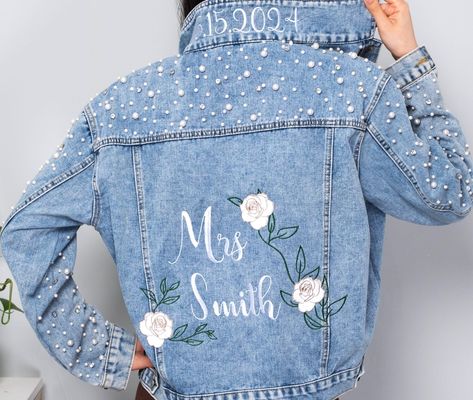 Step into bridal style with our personalized Bride Jean Jacket, a must-have for every future Mrs. This embroidered denim jacket is perfect for bridal showers, wedding festivities, and beyond. 👰 Personalized Perfection: Customize this denim jacket with the bride's name or "Future Mrs." for a unique and special touch. It's a timeless keepsake she'll cherish forever. 💍 Bridal Essential: Our pearl-studded jean jacket adds flair to engagement photos, bachelorette parties, and wedding day preparatio Wedding Jean Jacket, Bridesmaid Jean Jacket, Bride Jean Jacket, Jean Jacket Design, Pearl Jacket, Girls Denim Jacket, Embroidered Jean Jacket, Bride Jacket, Toddler Jeans