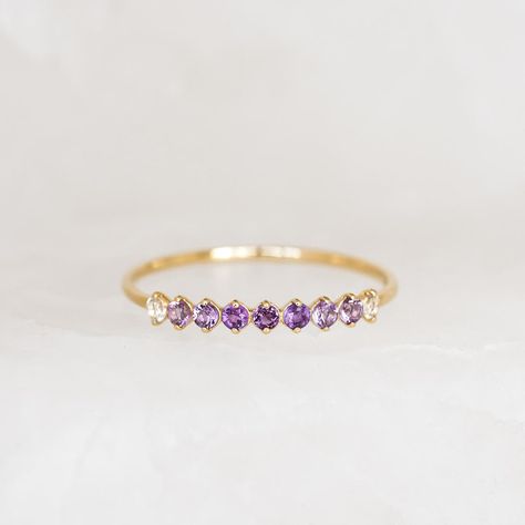 Inspired by the mystical allure of birthstones, this delicate 14k gold ring features an ombre gemstone arrangement of deep and light amethyst and white topaz. The mesmerizing transition of hues makes it a perfect and meaningful gift for yourself or a loved one born in February. Amethyst (February birthstone) is the stone of peace and serenity White topaz is the stone of truth and clarity 3 deep amethyst stones, each with a width of 1.75mm 4 light amethyst stones, each with a width of 1.75mm 2 Amethyst Wedding Band, Ombre Rings, February Birthstone Ring, February Birthstone Jewelry, Gold Ombre, Born In February, Purple Rings, Amethyst Stones, Peace And Serenity