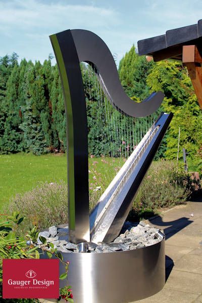 A stainless steel "harp" fountain... how clever! | #FountainIdeas #WaterFeatures #OutdoorFountain Fountain Front Yard, Fountain In Garden, Modern Water Fountain, Yard Water Fountains, Solar Fountain Ideas, Backyard Water Fountains, Diy Solar Fountain, Water Fountain Design, Patio Pond