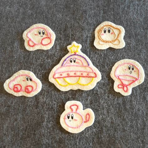 These hand-embroidered felt patches are inspired by Kirby's Epic Yarn! They have an iron-on adhesive backing for secure attachment to any jacket, bag, etc.! They can also be stitched on.  Note: Every design is hand-embroidered, making each piece unique! Your made-to-order patch may look slightly different from the one in the display pictures, but all the details will be exactly the same. Washing instructions: Color does not bleed when machine-washed. Iron-in adhesive is not machine-washable, but can be machine-washed if sewn on first. Delicate setting recommended. Kirby Tufting, Kirby Crafts, Kirby Embroidery Pattern, Kirby Embroidery, Pikmin Embroidery, Video Game Embroidery, Kirby Cross Stitch Pattern Free, Kirby Yarn, Kirby Needle Felting