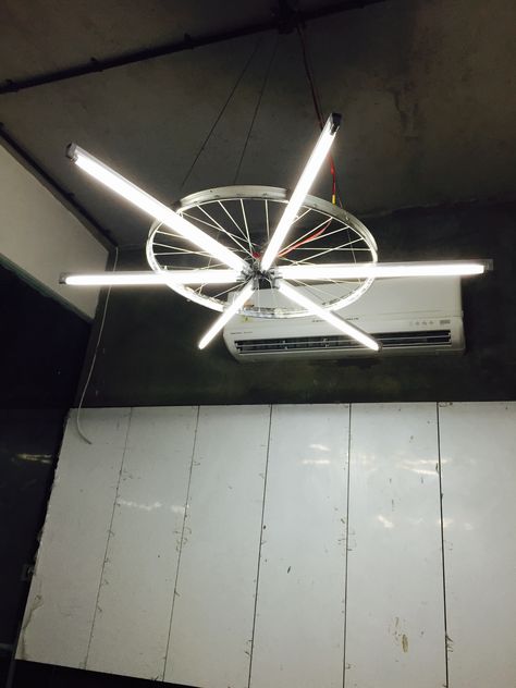 Abhishek Tank | Interior Designer #Formed a light using a cycle wheel tied T5 tube lights, hanged with the cable suspended from ceiling. Tank Interior, Cycle Shop, Tube Light, Diy Lamp, Ceiling Design, 인테리어 디자인, Metal Decor, Interior Designer, Ceiling Fan