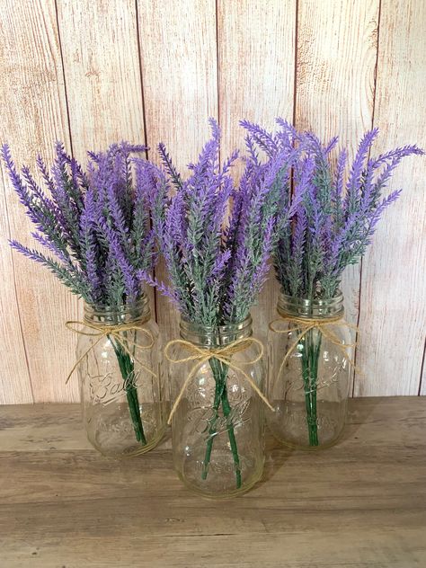 "These Lavender mason jars are perfect for wedding Centerpieces and bridal shower decor. These jars are also a great addition to your home decor, use as centerpieces or simple table decor.  Mason Jars are Quart Size Jars with twine attached at the top. Each jar has two purple faux lavender stems.  Lavender Bouquet is 14\" L Click my shop link below if you are interested in more styles of Mason Jars!  https://www.etsy.com/shop/TheCraftingJar" Rustic Table Decor Wedding, Purple Flower Centerpieces, Simple Table Decor, Purple Table Settings, Centerpiece Purple, Lavender Centerpieces, Lavender Wedding Theme, Farmhouse Wedding Decor, Purple Party Decorations