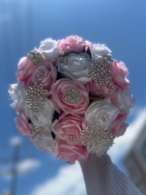 Handmade quinceañera bouquet with light pink and white color of roses. Finished off with silver brooches. *Please note brooches can change in style based on availability*   Decor can be changed upon request.  *This is a made to order bouquet* Pink White And Silver Wedding, Color Of Roses, Pink And White Bouquet, Satin Flowers Diy, Ribbon Rose Bouquets, Quinceanera Bouquet, Silver Wedding Decorations, Quinceanera Pink, Pink Quince