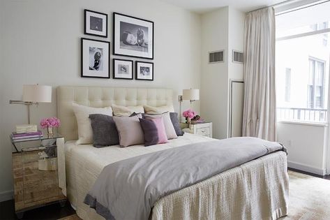 Contemporary bedroom features a black and white photo wall over a cream leather tufted headboard on bed dressed in ivory bedding, gray duvet an assortment of pink, purple and gray pillows flanked by mirrored nightstands situated under polished nickel swing-arm sconces with drum shades. Tufted Headboard Bedroom Decor, Tufted Headboard Bedroom, Small Space Storage Bedroom, Light Pink Bedrooms, Cream And White Bedroom, Blush Pink Bedroom, Beige Headboard, Leather Bedroom, Bedroom Neutral