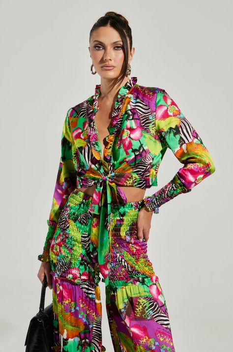 Globetrotting in the foreseeable future? This calls for The AKIRA Label On Vaycay Tie Front Crop Top. This vibrant blouse features a non-stretch satin composition, tropical collage patterning with zebra print detailing, a ruffled standing collar that ascends down the plunging neckline, and long sleeves with cinched, shirred elastic cuffs. Complete with a cropped silhouette, and a tie-front closure at the waist. Style with a lace bralette and the coordinating AKIRA Label On Vaycay Wide Leg Pant for a colorful warm-weather look. - 100% Polyester - No Stretch - Imported (all measurements are approximate from size small) - 16” Shoulder to Hem  - 24” Sleeves - 14.25” Shoulder to Shoulder - Model is 5’8” Product ID: 394093 Tropical Collage, Front Crop Top, Standing Collar, Wide Leg Pant, Stretch Satin, Lace Bralette, Plunging Neckline, Zebra Print, Shoulder To Shoulder