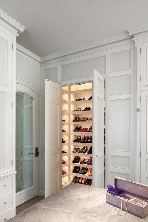 An expansive custom closet boasts wainscot walls framing double doors that open to a lighted shoe closet with sloped shelves. Luxury Closet Lighting, Closet Design Shoe Storage, Diy Rack Shelf, Master Closet Shoe Storage, Master Closet Shoe, Vanderhorn Architects, Diy Master Closet, French Eclectic, Kids Closets