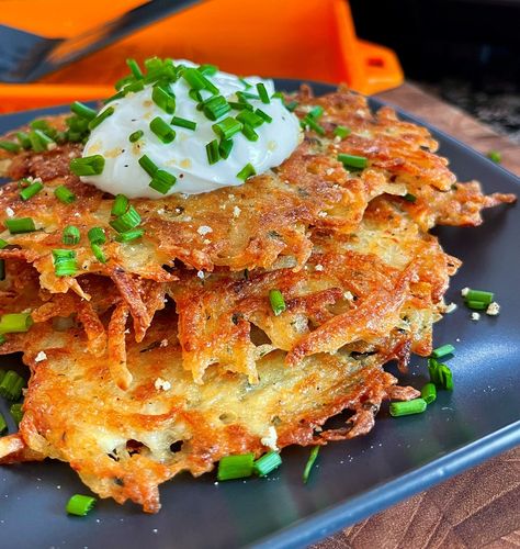 Crispy Potato Pancakes Recipe by BlackstoneBetty  Serves 4 Time: 30 minutes Difficulty: Easy Ingredients 2.5-3 pounds russet potatoes 1 medium yellow onion 3 large eggs, beaten 1/4 cup flour 1/2 tablespoon Blackstone Essential blend 1/2 teaspoon dried parsley  1/2 teaspoon garlic powder Dash of Tabasco sauce or pinch of cayenne pepper Sour cream, to serve Chives, to serve Directions Peel skin off potatoes. Using a box grater, grate potatoes into a large bowl full of cold water. Add a few ice Fried Potatoes Blackstone, Black Stone Fried Potatoes, Hashbrown On Blackstone, Pancakes Blackstone, Cooking Potatoes On Blackstone Griddle, Potato’s On The Blackstone, Outdoor Pizza Oven Recipes, Crispy Potato Pancakes, Crispy Breakfast Potatoes