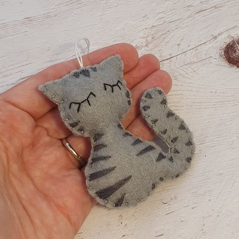 🐱💫 This handmade cutie is the purr-fect addition to your holiday decor or a sweet gift for any cat lover! 😻🧵 With its soft gray stripes and cute little face, this felt tabby is stitched with love and care to bring cozy cat vibes to your tree. 💖 #HandmadeInHungary #FeltTabbyCat #GrayTabbyOrnament #CatLovers #HolidayDecor #FeltCrafts #UniqueGifts #FeltArtistry #ShopSmall #EtsyFinds #ShopifyTreasures #CozyVibes #WhimsicalDecor #FelineFun #HandmadeWithLove #CraftersOfInstagram #CraftingJoy 😻🐾💫 Gifts For A Friend, Clothing Keepsake, Felt Cupcakes, Diy Felt Christmas Ornaments, Grey Embroidery, Felted Projects, Selling Crafts, Pet Christmas, Crafty Christmas