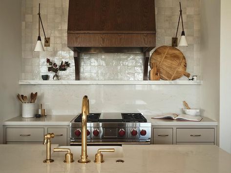 A brown wooden range hood is fixed to gray glazed grid backsplash tiles over a marble spice shelf fixed over a marble cooktop. Cooktop Backsplash, Mandy Cheng, Shelf Design Ideas, Marble Top Kitchen Island, Wooden Range Hood, Light Grey Kitchen Cabinets, Kitchen Floating Shelves, Santa Barbara Style, Light Gray Cabinets