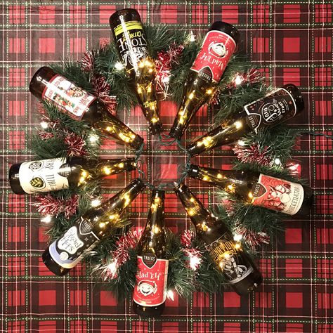 My take on a beer bottle wreath!!   Metal wreath frame, beer bottles adhered with E6000 glue, green garland, red garland, white lights, and a few pipe cleaners to hold things in place. Beer Bottle Christmas Tree, Beer Bottle Christmas Crafts, Beer Christmas Decorations, Beer Can Decorations, Christmas Pub Decorations, Beer Wreath, Bar Management, Beer Crafts, Tacky Christmas Party