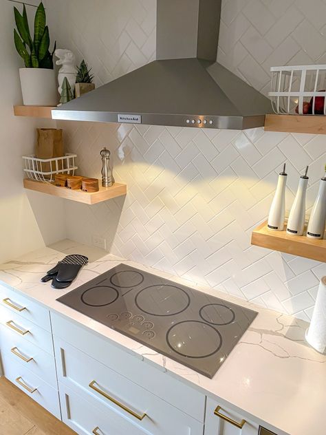 A kitchen with a grey induction cooktop, white cabinets, white tile, and brass pendant lights. Range Hood Over Induction Cooktop, Induction Cooktop Kitchen, Counter Top Stove, Kitchen Cooktop, Myths And Facts, Induction Range, Kitchen Hoods, Electric Cooktop, Common Myths