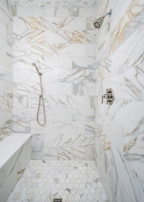 The marble walk-in shower is shot through with veins of gray and gold. White And Gold Shower Tile, Gold Shower Tile, Tile Bathrooms, Grey Ceramic Tile, Luxury Bathroom Master Baths, Marble Tile Bathroom, Restroom Design, Marble Showers, Gold Shower