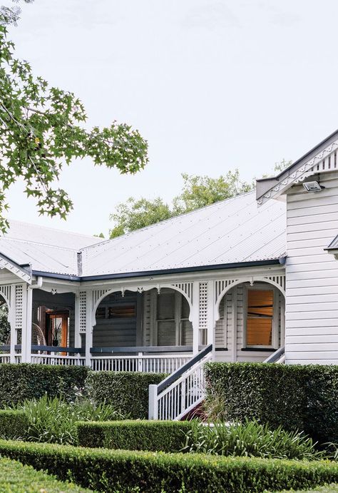 A white weatherboard Queenslander home surrounded by landscaped low hedges. Queenslander Homes Exterior, French Provincial Farmhouse, Brunswick House, Queenslander House, Stone Mansion, Australian Homes, Colonial House, Brickwork, Underfloor Heating