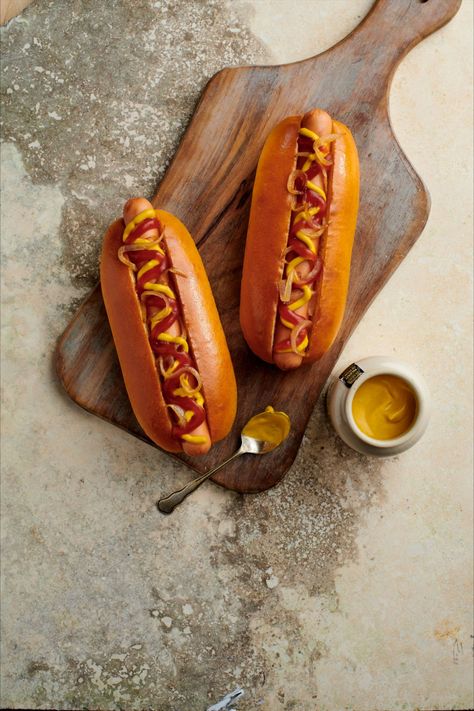 Two hot dogs topped with ketchup and mustard on a wooden board with a pot of mustard and a spoon next to it. Hot Dog Rolls, Dog Bread, Brioche Rolls, Yellow Mustard Seeds, Simple Things In Life, Recipe Email, Delivery Menu, Brioche Buns, St Pierre