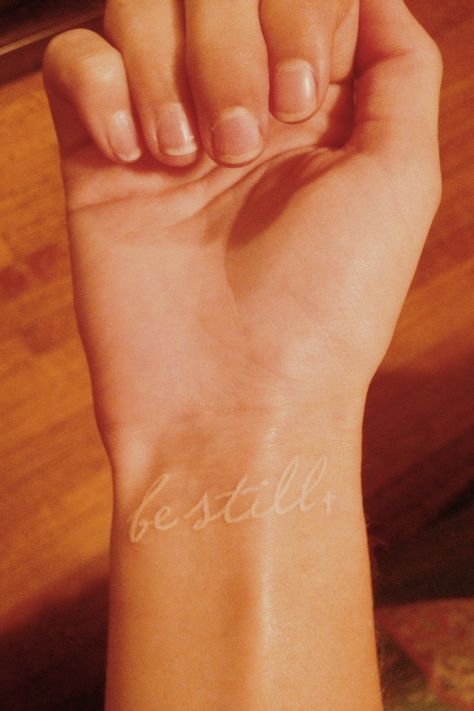 White Letter Tattoo, Be Still Bible Verse Tattoo, Be Still My Soul Tattoo, Be Still Finger Tattoo, Be Still Tattoo Wrist, White Ink Wrist Tattoo, Be Still Fine Line Tattoo, Be Still And Know Tattoo With Cross, White Ink Script Tattoo