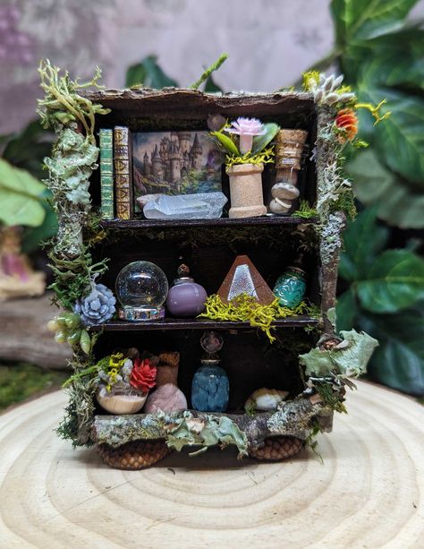 "Due to the items we use for this piece, this is really made for the inside fairies.  One of a kind handcrafted Fairy Bookshelf. Same fun items as our other bookshelves, but with a slightly different style. This one-of-a-kind fairy shelf is designed by the fairies - crafted by me! This piece will be handcrafted when ordered and bottles and little shelf accessories may vary slightly from the photo depending on what we have in stock. We make all of our special bottles and shelves in our workshop a Fairy Garden Shelf, Fairy House Furniture Diy, Fairy Garden Book Nook, Air Dry Clay Fairy Garden Accessories, How To Make Fairy Garden Accessories, Fairy House Diy Natural Materials, Fairy Crafts For Adults, Fairy House Interior, Fairy Furniture Diy