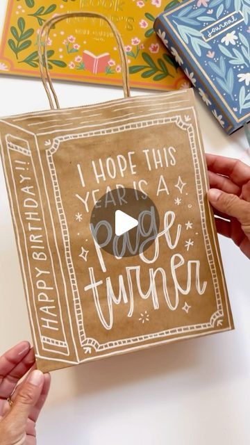 Pippi Post | Bookish Merch ✨ on Instagram: "Try this for your next gift bag ✨📖 

I’m obsessed with how this one turned out and I can’t wait to add books and bookish merch inside! 🥳

To get the look, I used a brown craft bag and my favorite white marker. You can stencil out the book and lettering before you start with a pencil, too! 

To get the links for all the supplies, comment LINK below 👇 

#pippipost #bookishmerch #bookmerch #bookishshop #bookishbirthday #bookbirthday #bookishideas #handletteredgifts #happyhandlettering" Diy Bookish Crafts, Wrapping Books For Gifts, Book Wrapping Ideas, Diy Gift Bags Paper, White Marker, Book Baskets, Bookish Merch, Birthday Packages, Unique Gift Wrapping