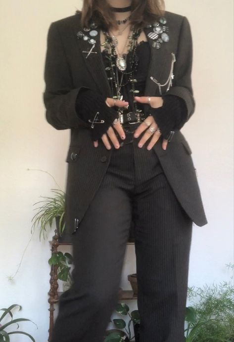 A mid-sized person/girl grey/dark green striped suit decorated with lots of oins and chains, black arm warmers, black platform dr. Martens and multiple crystal rings and bracelets. 		The person is also wearing multiple silver necklaces, a big one in form of a cross. Alternative Semi Formal, Aesthetic Suit Outfit, Corset And Suit Outfit, Alt Suit Outfit, Alt Suit Aesthetic, Punk Blazer Outfit, Punk Prom Suit, Masc Goth Outfits Formal, Punk Corset Outfit