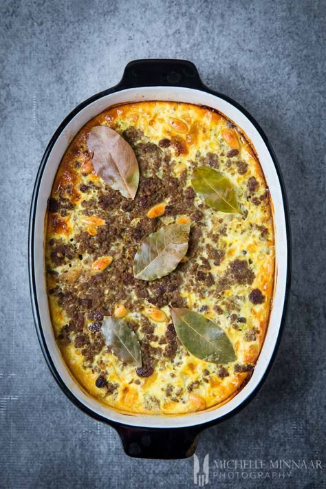 Bobotie is the national dish of South Africa. This baked beef casserole makes a hearty family meal for all to enjoy. Indulge in the exotic flavours of the curry spices, dried fruit, nuts and the texture and richness of the minced meat. Serve with geelrys, boereboontjies and a glass of delicious red South African wine. Bobotie Recipe South Africa, South African Recipe, Bobotie Recipe, Mince Dishes, African Recipe, South African Dishes, South African Wine, African Cooking, Mince Recipes