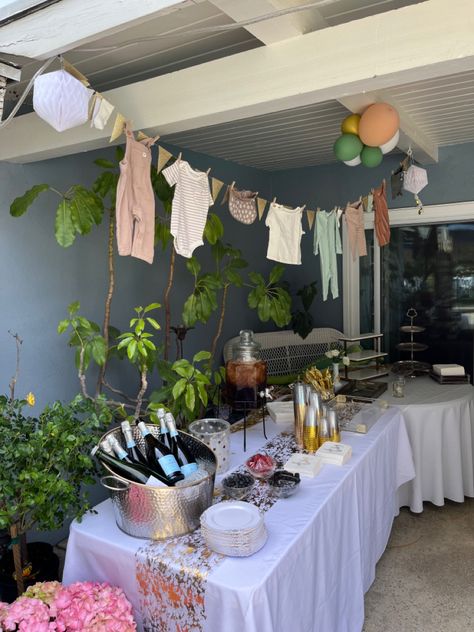 Clothes line with baby clothes and glitter triangles hanging over a dessert table. Baby Clothes Baby Shower Decor, Baby Clothes Line Decor, Clothes Line Baby Shower Decoration, Baby Shower Clothesline Decoration, Onesie Clothes Line Shower Ideas, Clothesline Baby Shower Decor, Baby Shower Clothes Line, Shrek Baby, Neutral Baby Shower Decor