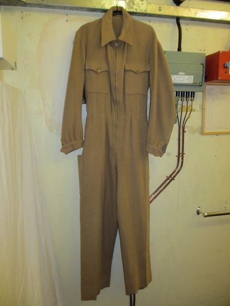 Siren Suit (1940-1945) | Due to the war, siren suits became popular in the early 1940s. These suits often zipped up the front, as shown in the picture, and had hoods to be easily slipped on over nightclothes during air raids. The siren suit pictured shows how they had long pants and long sleeves to cover all skin. Siren Suit 1940s, Interesting Suits, Vis Dev, Man Outfit, Alex Mill, Group Project, Make Do And Mend, The Siren, The Blitz