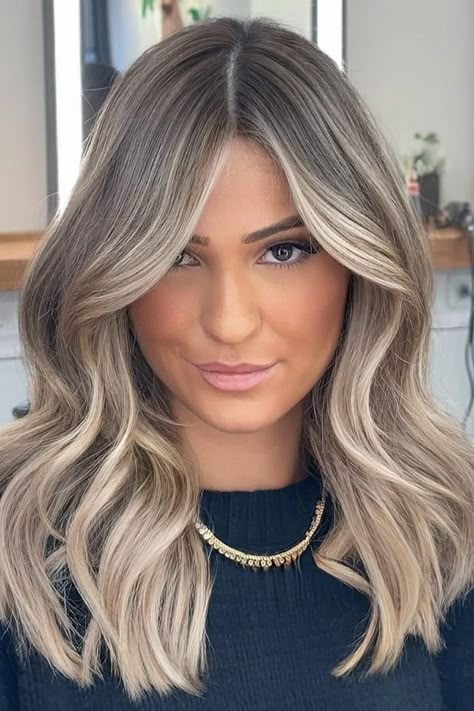 Full-bodied medium-length lob with face-framing layers and a center part. Features a cool-tone balayage with ash blonde highlights that blend seamlessly into a darker base for added dimension. The style has loose waves that create volume and movement.  // Photo Credit: Instagram @zaferarsanoglu_official Ash Blonde Balayage With Face Framing, Blonde Balayage Blended Roots, Balayage Silver Hair Ash Blonde, Medium Blonde And Brown Hair, Blonde Hair Ash Roots, Cool Toned Blonde And Brown Hair, Blonde Balayage With Medium Length Hair, Balayage Hair Blonde Mid Length, Brown To Cool Blonde Balayage