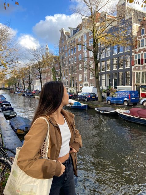 girl in amsterdam standing by canal, streetwear outfit, brown jacket, tote bag, claw clip, canal houses Amsterdam Aesthetic Pictures, Germany Instagram Pictures, Netherlands Photo Ideas, Amsterdam Pictures Ideas, Amsterdam Instagram Pictures, Amsterdam Outfit Summer, Amsterdam Aesthetic Outfit, Amsterdam Photo Ideas, Paris Trip Outfits