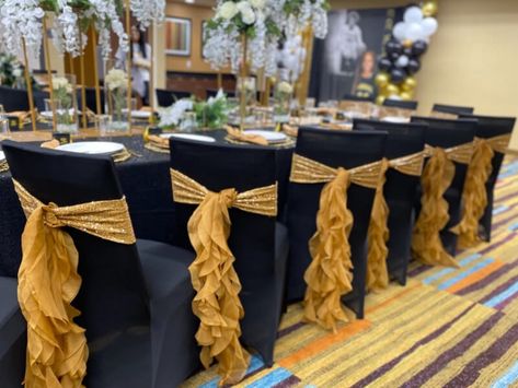 Prepare the venue for your big event using the regal decoration supplies to give out a royal look. Satisfy your aesthetic taste by using black spandex stretch folding chair covers and gold spandex chair sashes on the chairs topped with gold chiffon hoods. Opt for our black polyester tablecloths to dress your tables and accentuate them with artificial wisteria vine garlands dangling from our metal flower stands for an extra elegant look. Black Chair Covers With Gold Sash, Masquerade Party Centerpieces, Wedding Diy Decorations, Black Chair Covers, Birthday Chair, Golden Chair, Gold Reception, White Chair Covers, Party Decorations Table