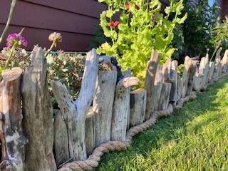 Driftwood from the beach, rope from the hardware store (or find your own), and a pneumatic nail gun to make this easy garden border Driftwood Yard Ideas, Using Driftwood In The Garden, Landscaping With Driftwood, Driftwood Garden Border, Garden Beach Ideas, Driftwood Landscaping, Driftwood Garden Ideas, Beach Garden Ideas, Prairie Landscaping