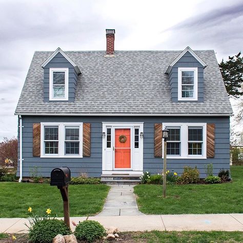 How adorable is this Cape Cod style home? The shutters are a unique touch and I love the bold orange on the door #orange #frontdoor #shutters Navy Blue Houses, Orange Front Doors, Best Front Door Colors, Blue Siding, Color Door, Painted Houses, Best Front Doors, Orange Door, Cape Cod Style House