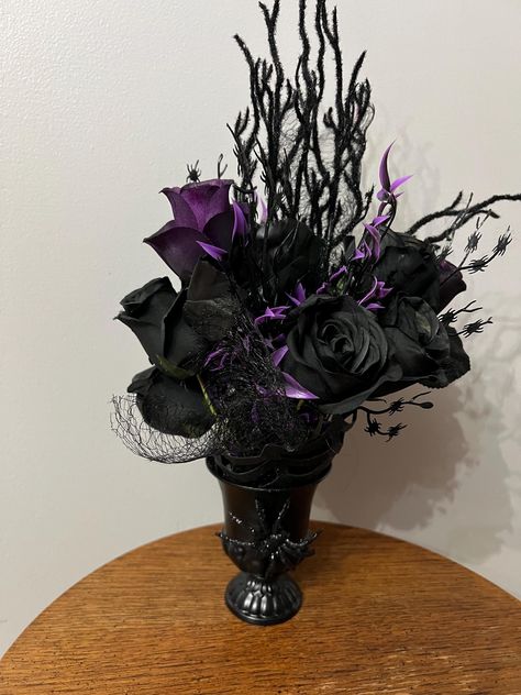 Handmade gothic home decor floral arrangement, painted black distressed metal  vase with black and purple roses & stems, tall branch sprays in pedestal vase with fake spider  Arranged into pedestal vase,  gothic Halloween centerpiece, table top decor  Pictures do not do justice to this piece,  This stands approx 14"  tall with the flowers, the vase is 4.5" tall  Ready to ship Gothic Centerpieces, Vase Gothic, Black And Purple Roses, Gothic Vase, Halloween Vase, Home Decor Floral Arrangements, Fake Spider, Gothic Floral, Halloween Centerpiece