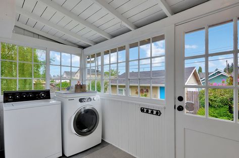 This mudroom or sun porch is at the back of an old Tacoma Craftsman home and is classically charming with its paned windows and white paint. There's room for laundry, workspace, and storage, but I'd be tempted to set up the wicker chair and cushions back there.   #mudroom #sunporch #craftsmanhome #dugganhomes #laundryroom #backporch #enclosedporch Laundry Room With Lots Of Windows, Laundry On Deck, Laundry Room On Sun Porch, Laundry Room On Porch, Porch Laundry Room Ideas, Laundry Porch Ideas, Screen Porch Mudroom, Back Porch Mudroom Ideas, Back Porch Laundry Room Ideas