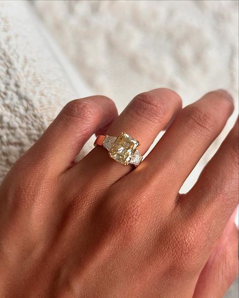 Adore this recent bespoke creation, featuring a 3.1ct radiant cut champagne moissanite, a flat wide band, and trapezoid accent stones 🤍 Details: - 3.2ct radiant moissanite - 2x 0.5ct trapezoid moissanites - 18k yellow gold - 3.9mm wide shank Vintage Yellow Diamond Ring, Trilogy Engagement Ring And Wedding Band, Engagement Rings Yellow Diamond, Whitelaw Gold, Multi Stone Engagement Ring, Wide Band Wedding Ring, Cool Engagement Rings, Yellow Diamond Engagement Rings, Champagne Moissanite