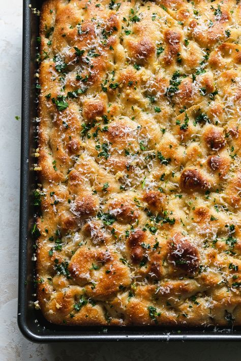 This Garlic Bread Focaccia is fluffy on the inside, crunchy and deeply golden on the edges, and doused in melted garlic butter. It's undoubtedly on of the best things to ever come out of my kitchen. It's the perfect vehicle for sandwiches, served with soup, dipped in more garlic butter (!!), or just simply eaten on its own. Salty, garlicky, buttery, fluffy, crunchy, golden brown perfection! Foccacia Bread Half Baked Harvest, New Years Foccacia, Focaccia And Dip, Homemade Dinner Bread, Superbowl Bread Ideas, Foccacia Bread Sheet Pan, Party Bread Recipes, Garlic Herb Focaccia Bread, Cheesy Garlic Sourdough Foccacia Bread