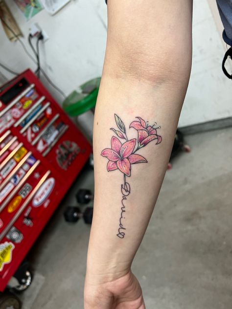 Name tattoo with lily flowers Lily Tattoo With Name, Lily Name Tattoo, Name Tattoos With Flowers, Nancy Tattoo, Flower With Name Tattoo, Small Lily Tattoo, Flower Name Tattoo, Letter R Tattoo, Name Flower Tattoo